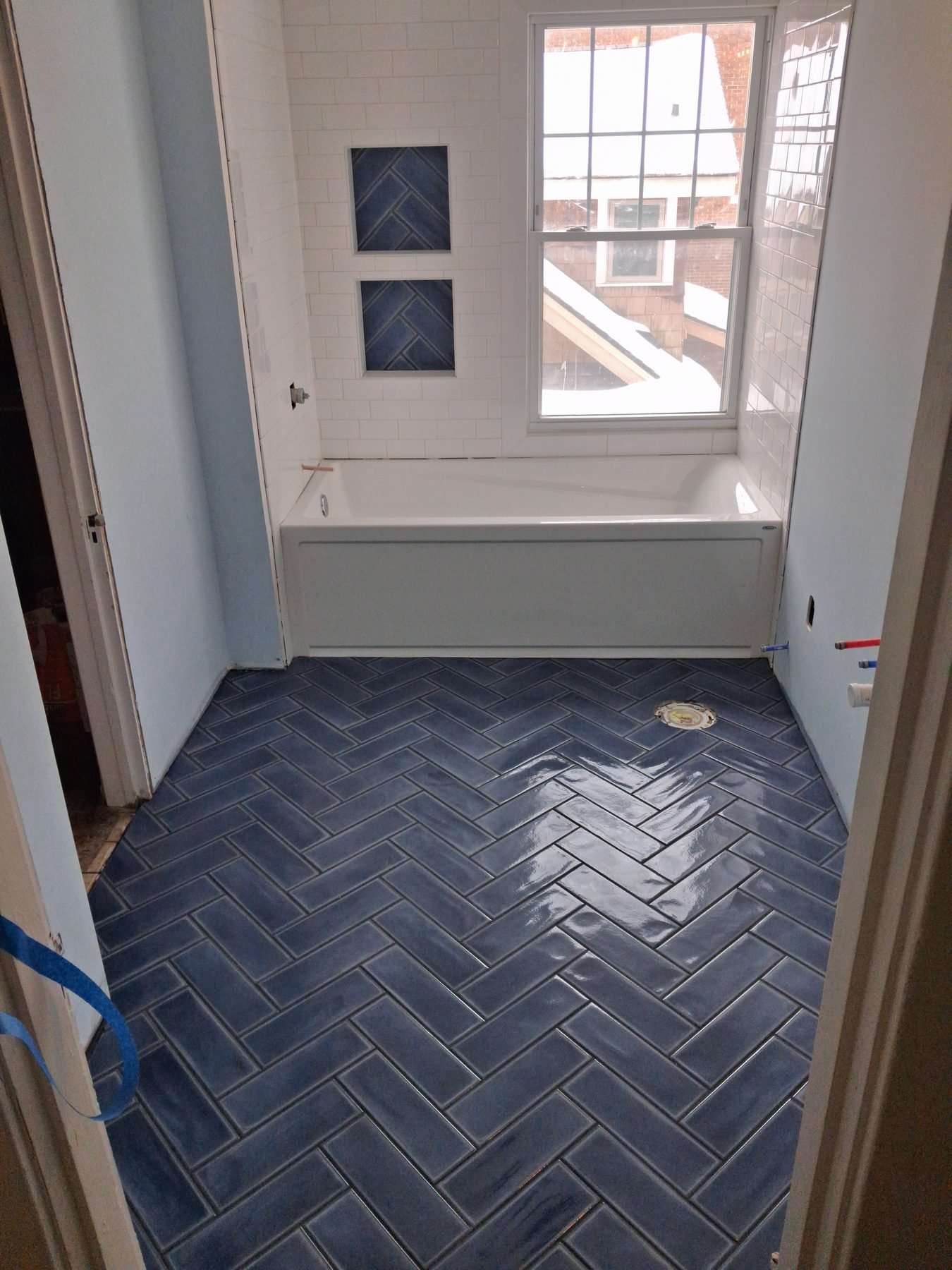 Navy herringbone floor & subway tub wall