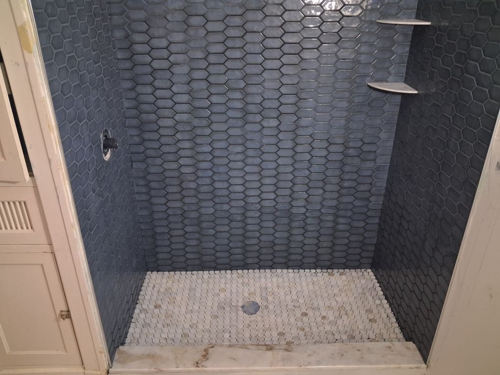 Navy hex shower with marble penny floor