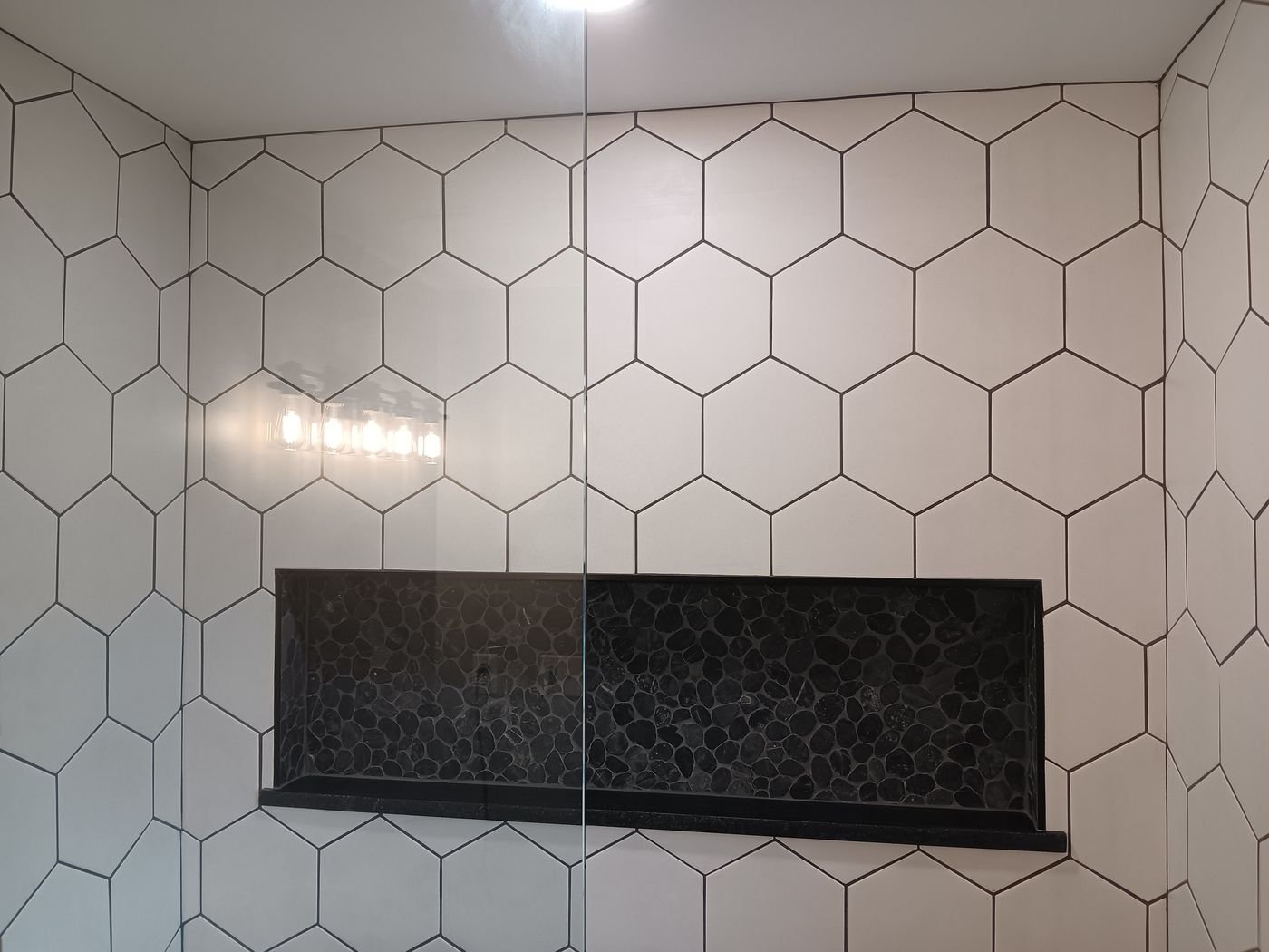 White hex shower, black pebble niche
